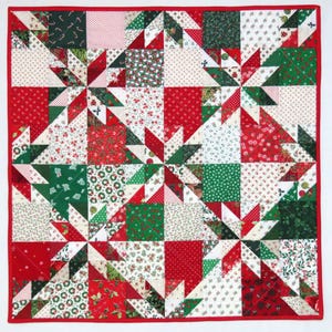 Peut inclure: Une courtepointe carrée avec une bordure rouge. La courtepointe présente un motif d'étoiles répétées dans des tissus rouges, verts et blancs avec des motifs floraux et à pois. La courtepointe est une décoration de vacances festive.