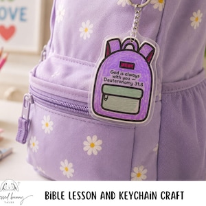 May include: A light purple backpack with white daisy patterns and a matching zipper. A keychain with a backpack design is attached. The keychain has the text "God is always with you - Deuteronomy 31:8".