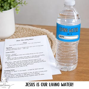 May include: A clear plastic water bottle with a blue label that reads "LIVING WATER" and a space for a name. The bottle sits next to a printed lesson plan titled "Jesus - Our Living Water". A small potted plant is in the background.