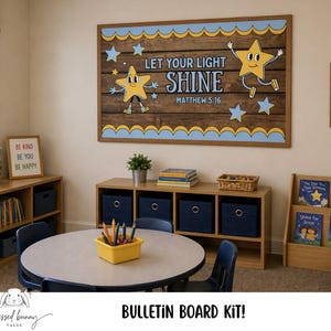 Peut inclure: Une scène de classe avec un grand tableau d'affichage affichant "Let Your Light Shine" et des illustrations d'étoiles. La pièce comprend une table ronde, des chaises et des étagères avec des livres. Un panneau encadré affiche les mots "Be Kind, Be You, Be Happy".