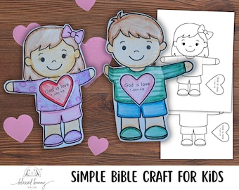 May include: Colorfully illustrated paper dolls of a boy and girl with the text "God is love" on their chests. The girl has a pink bow and the boy has brown hair. Pink heart cutouts and a sheet of black and white paper dolls are also visible.