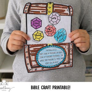 May include: A child holds a paper craft treasure chest with colorful gemstone cutouts labeled "love," "help," "be kind," "share," and "pray." The chest features a Bible verse and the words "Bible Craft Printable!"