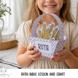 May include: A child holds a paper basket craft labelled "RUTH" filled with paper wheat stalks. The basket has a white and grey diamond pattern. The image is part of a "RUTH-BIBLE LESSON AND CRAFT" project.