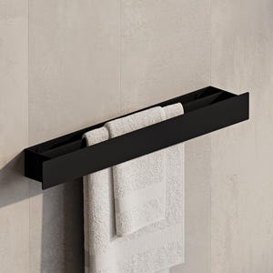 Peut inclure: Un porte-serviettes moderne en métal noir fixé sur un mur carrelé gris clair. Deux serviettes blanches pliées avec des détails rayés sont suspendues au porte-serviettes. Le porte-serviettes est rectangulaire avec un dessus plat et une étagère inférieure.