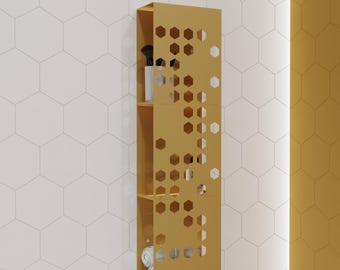 May include: A vertical mustard yellow wall-mounted storage unit featuring three open shelves and a decorative front panel with a laser-cut hexagonal pattern. The unit holds various small items, including white cylindrical containers and rolled towels.