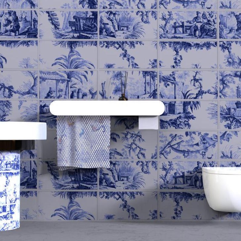 May include: A wall covered in rectangular tiles featuring a blue and white toile pattern depicting pastoral scenes with figures, trees, and structures. A white shelf holds a patterned towel, and a white sink and toilet are visible.