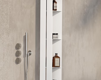 May include: A tall, vertical white metal shower shelf unit with four open compartments. The unit is mounted against a gray tiled wall and holds several brown amber-colored plastic bottles with black pump dispensers and a small black jar.