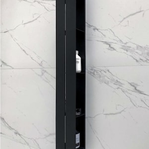 Peut inclure: Une étagère de salle de bain en métal noir avec quatre étagères. L'étagère est fixée à un mur en marbre blanc.