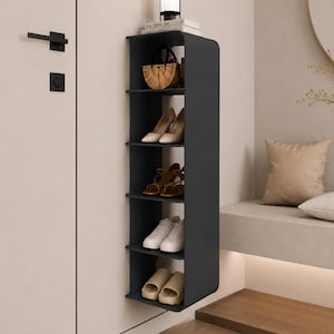 Puede incluir: Una estantería de pared de color gris oscuro con cinco niveles abiertos. El estante superior sostiene una pequeña lámpara y libros, mientras que los cuatro inferiores contienen un bolso trenzado, tacones beige, sandalias marrones, zapatillas blancas y sandalias tipo pala beige.