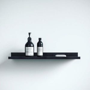 Puede incluir: Un estante negro con dos botellas negras de loción corporal y jabón. Las botellas tienen etiquetas blancas con el texto "Lusso" y "Black Sea". Una barra de jabón blanca está en el estante.