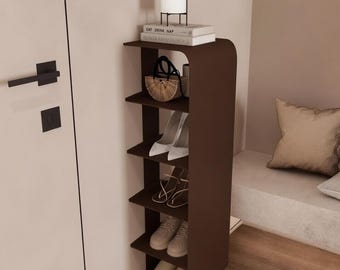 May include: A dark brown, wall-mounted, vertical shelving unit with five open tiers. The top shelf holds two stacked books and a white lamp with a black wire frame. The lower shelves contain a woven handbag, white heels, sandals, and sneakers.