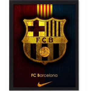 Puede incluir: Impresión enmarcada con el escudo del FC Barcelona en oro y negro, sobre un fondo rojo y azul. El nombre del equipo, FC Barcelona, está impreso debajo, con el logotipo de Nike en la parte inferior.