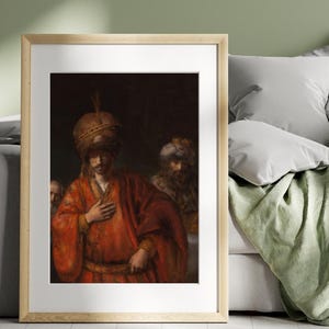 May include: Framed print of a historical painting featuring a man in a red robe and turban, with two other figures in the background. The artwork is displayed in a light wood frame.