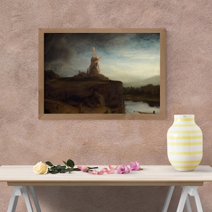 May include: A framed landscape painting depicts a windmill on a hill overlooking a body of water. The artwork features a cloudy sky and a muted color palette. A yellow and white striped vase, along with roses, sits on a wooden table.