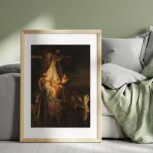 May include: Framed art print of a classical painting depicting a religious scene. The artwork features figures gathered around a cross, with a somber and dramatic atmosphere. The color palette is dominated by dark tones and highlights.