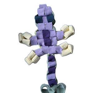 Könnte beinhalten: Ein handgehäkeltes Krokodil in Lila-, Creme- und Grüntönen. Der Körper ist ein Webmuster mit Schwanz und Beinen. Der Text "Häkelanleitung -Perlen Krokodil-" steht oben. Der Text "by HandsOnHobbies" steht unten.