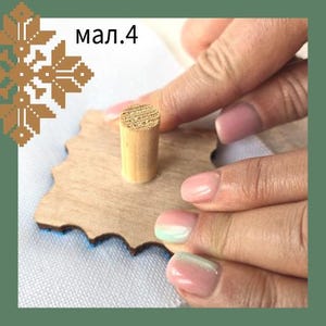 May include: A light-coloured wooden peg is inserted into a wooden, star-shaped cutout. The cutout has a blue border. The text "мал.4" is in the upper left corner. The background is a white surface.