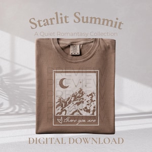 May include: A brown t-shirt featuring a rectangular graphic print of a mountain range under a crescent moon and stars. The text "there you are" is printed in a cursive script at the bottom of the graphic. The shirt has a crew neckline.