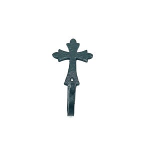 May include: A dark green, wrought iron wall hook shaped like a cross. The hook features an ornate design and a loop for hanging. The cross has a textured surface and is set against a white background. The hook is likely made of iron.