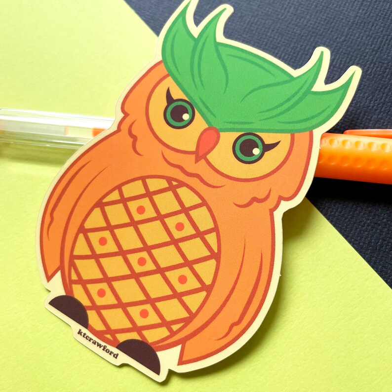 A die cut sticker of an orange owl that resembles a pineapple. The owl has yellow accents on its belly and around its green eyes. The top of its head is green.