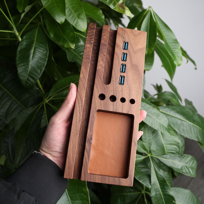 May include: A wooden desktop organizer with a built-in USB hub. The organizer has slots for pens, pencils, and other office supplies. It also has a leather-like pad for a phone or other small items.