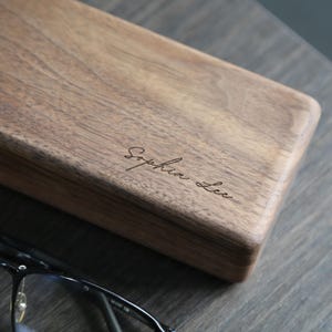 May include: A wooden box with the name "Sophia Lee" engraved on the top. The box is made of dark wood and has a smooth finish.