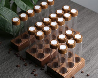 May include: A set of 18 clear glass spice jars with wooden lids and a white label on each lid. The jars are arranged in two rows on a wooden stand.
