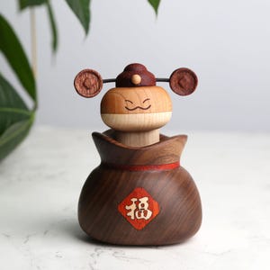 以下が含まれることがあります： 赤い帽子をかぶった笑顔のキャラクターの置物。茶色の金袋を持ち、袋には「福」の文字が書かれている。