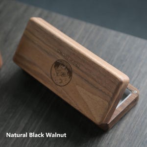 May include: A wooden box with a hinged lid, made of natural black walnut. The box has a circular design engraved on the top with the words "CHLOE BROWN".