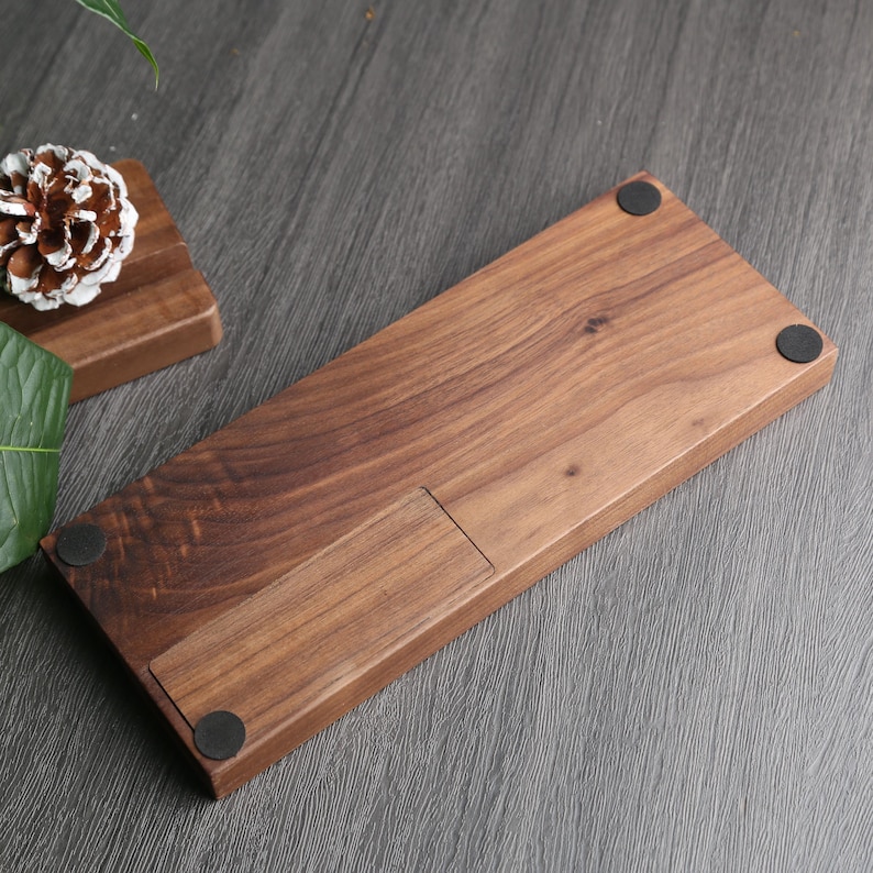 May include: A dark brown wooden keyboard tray with a cutout for a wrist rest. The tray has four black rubber feet on the bottom.