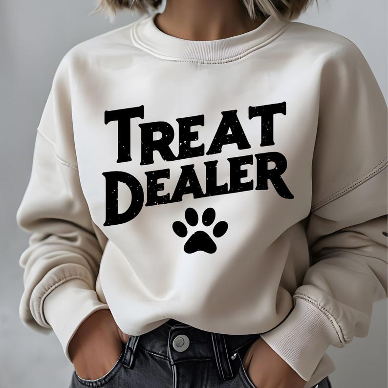 May include: A cream colored sweatshirt with the text "Treat Dealer" in black lettering and a black paw print below the text.