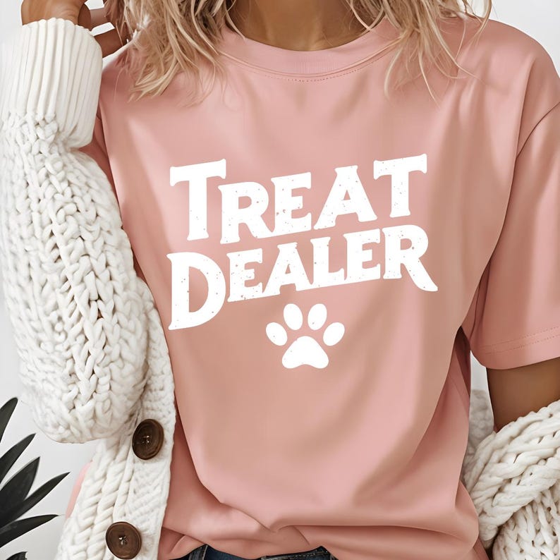 May include: A pink t-shirt with the text "Treat Dealer" in white with a white paw print below the text.
