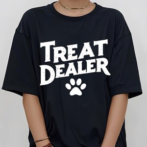 May include: Black t-shirt with white text that reads "Treat Dealer" and a white paw print.