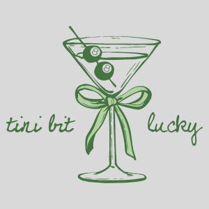 May include: A green martini glass with a green bow and two green olives with the number "8" on them. The text "tini brit" is on the left and "lucky" is on the right.