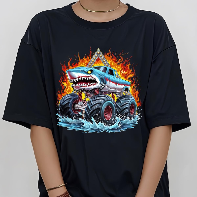 May include: Black t-shirt with a graphic of a blue and white monster truck with a shark head. The truck is driving through water and flames.