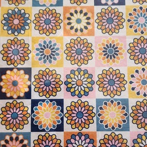 May include: A repeating pattern of colorful floral designs. Each flower is composed of layered petals in shades of orange, yellow, pink, and blue, set against a checkered background of various colors including white, blue, and orange.