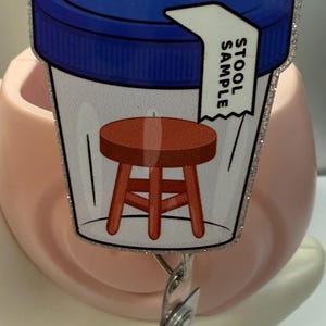 May include: A white plastic container with a blue lid and a label that says "Stool Sample". Inside the container is a cartoon image of a brown stool.