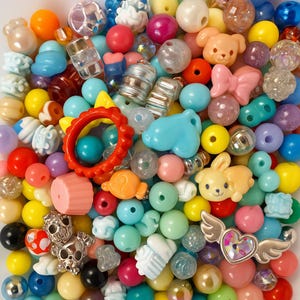 May include: A colorful assortment of beads in various shapes and sizes. The collection includes round, heart, and animal-shaped beads in shades of pink, blue, yellow, and green. There are also clear and metallic beads, perfect for jewelry making and crafts.