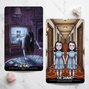 May include: Two rectangular tarot cards featuring horror movie illustrations. The left card shows a figure emerging from a television screen with the text THE RING. The right card depicts two identical children in a hallway with the text THE SHINING.
