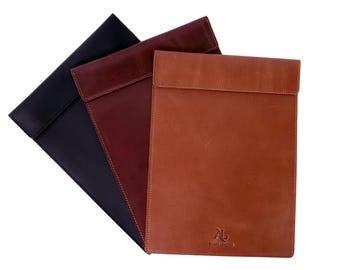 以下が含まれることがあります： 黒、ボルドー、茶色の3つの革製ラップトップスリーブ。スリーブはフラップクロージャーで、高品質の革で作られています。茶色のスリーブには、スタイリッシュなフォントで「AL」という文字が書かれています。