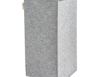 Puede incluir: Un cesto de ropa de fieltro gris con dos asas en la parte superior. El cesto es alto y rectangular.