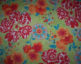 May include: A green fabric with a floral pattern featuring red, orange, blue, and white flowers. The flowers are stylized and have a tropical feel.