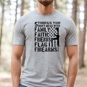 May include: A gray t-shirt with a black graphic that says "5 Things You Don't Mess With: Family, Faith, Friends, Flag, Firearms". The graphic also includes a stylized American flag and a rifle.