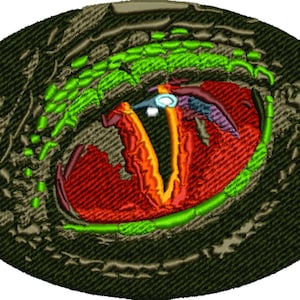 Puede incluir: Primer plano de un parche de ojo de dragón bordado en verde, rojo y amarillo. El ojo está rodeado de una textura escamosa verde oscuro.