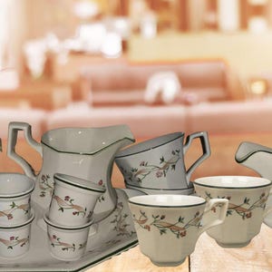 May include: A white tea set with a floral pattern on a tray. The set includes a teapot, creamer, sugar bowl, and four cups.