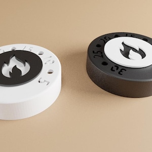 Può includere: Due timer rotondi, uno nero e uno bianco, con un simbolo di fiamma al centro. I timer hanno numeri sul bordo, che indicano gli incrementi di tempo. Il timer bianco ha una fiamma nera, e il timer nero ha una fiamma bianca.