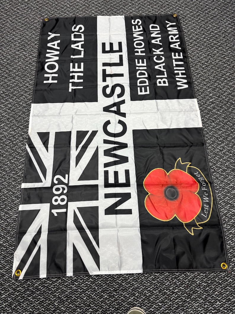 May include: Black and white flag with the text "HOWAY THE LADS" and "NEWCASTLE" in white. Features a Union Jack design and a red poppy with "Lest We Forget" text. Includes the year "1892".