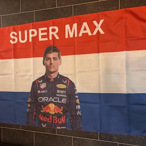 Puede incluir: Una bandera roja, blanca y azul con las palabras "SUPER MAX" impresas en blanco. Una foto de un piloto de carreras con un traje de carreras rojo, blanco y azul está en el centro de la bandera.
