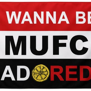 May include: A rectangular horizontal banner featuring three horizontal stripes in red, white, and black. The text I WANNA BE is in white on the red stripe. MUFC is in black on the white stripe with red devil logos on each side. ADORED is in white and red on the black stripe with a yellow lemon slice replacing the letter O.