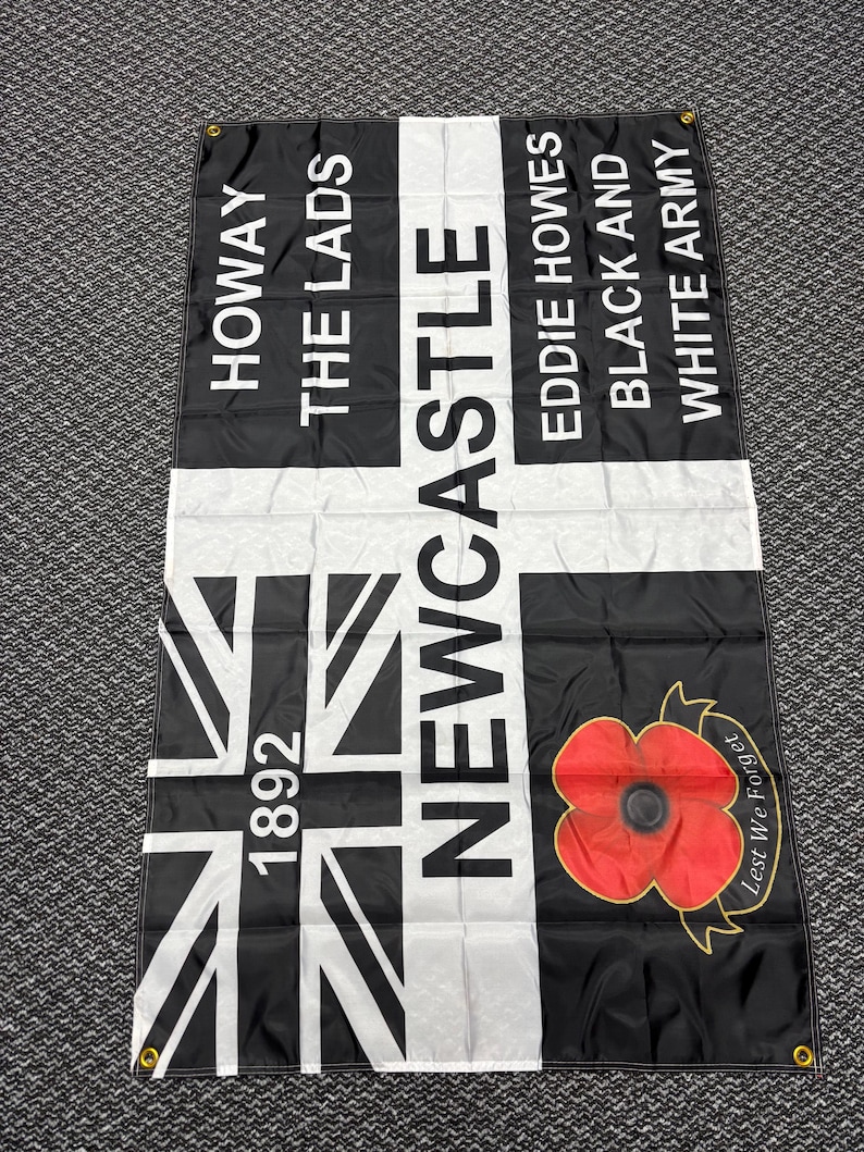 May include: Black and white flag with text reading "HOWAY THE LADS NEWCASTLE EDDIE HOWES BLACK AND WHITE ARMY" and a Union Jack design. Features a red poppy with "Lest We Forget" text.